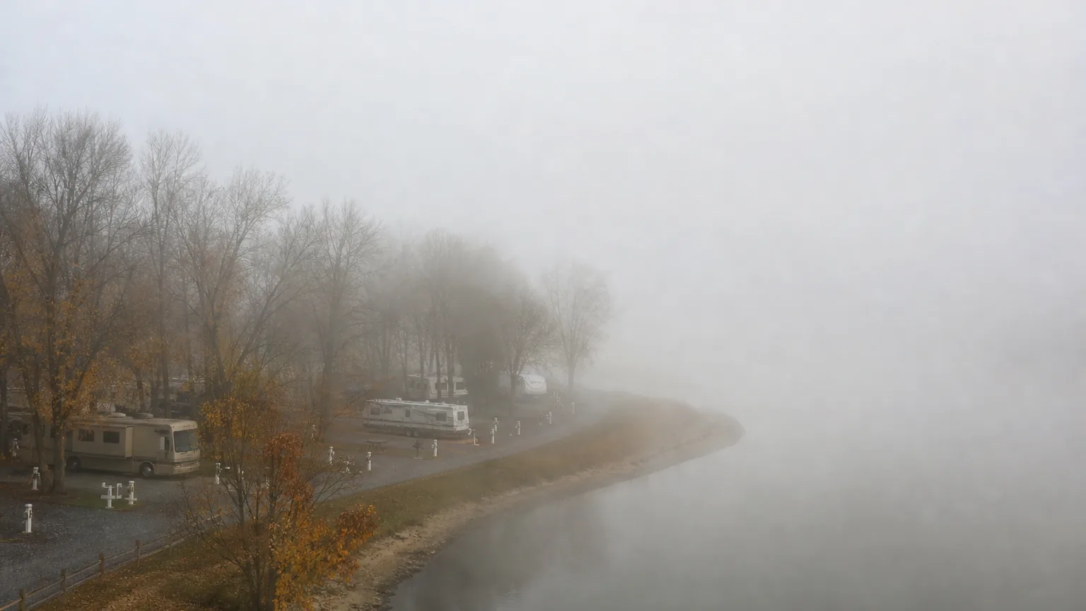 River bend beside RV park sites in late autumn fog