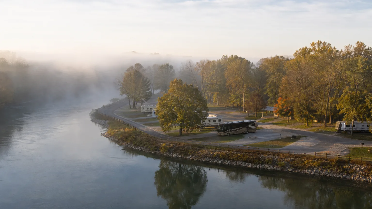 River bend with sites along it at an RV park in morning fog