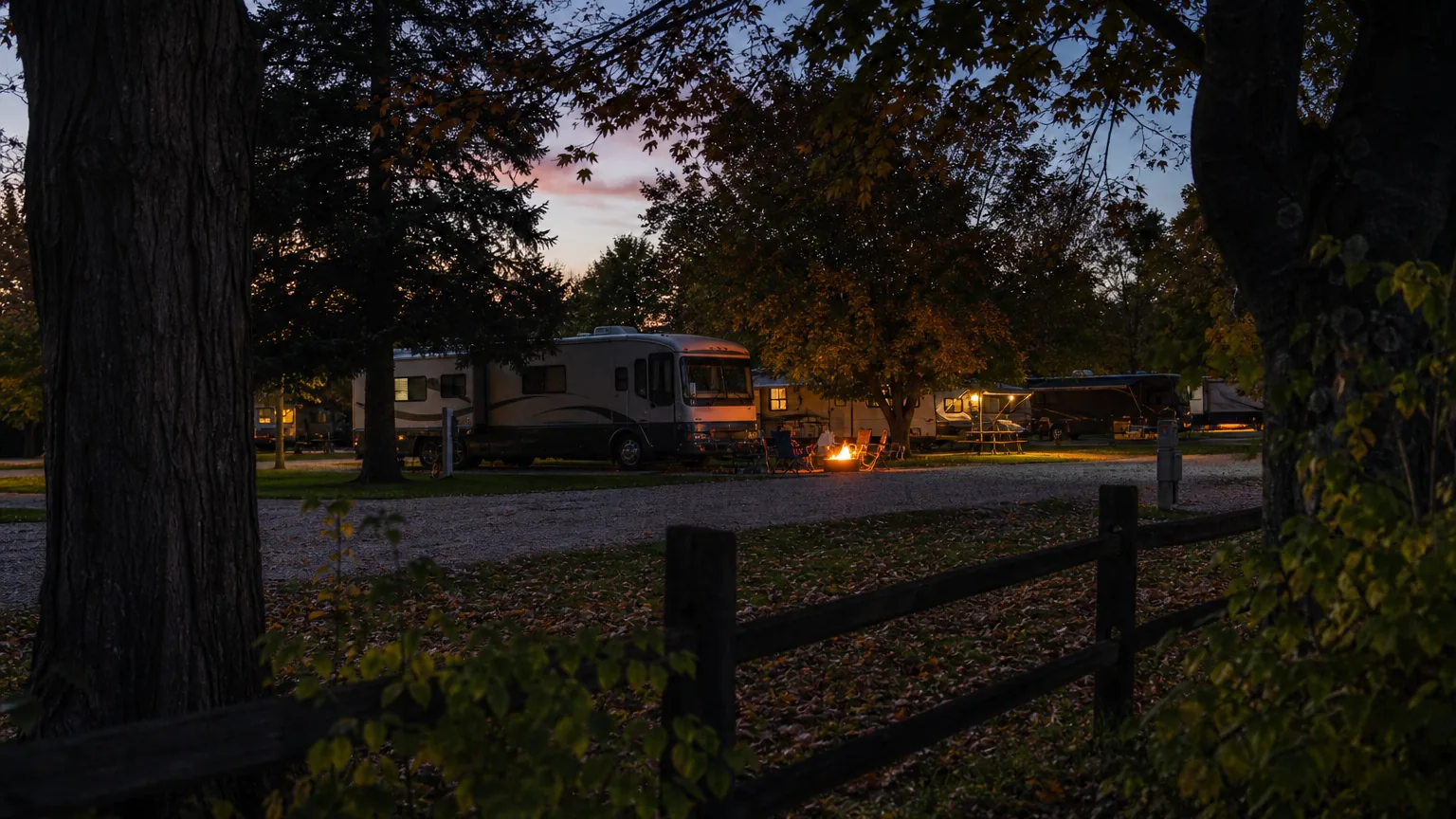 Occupied site with a fire ring at an RV park in dusk with campfire glow