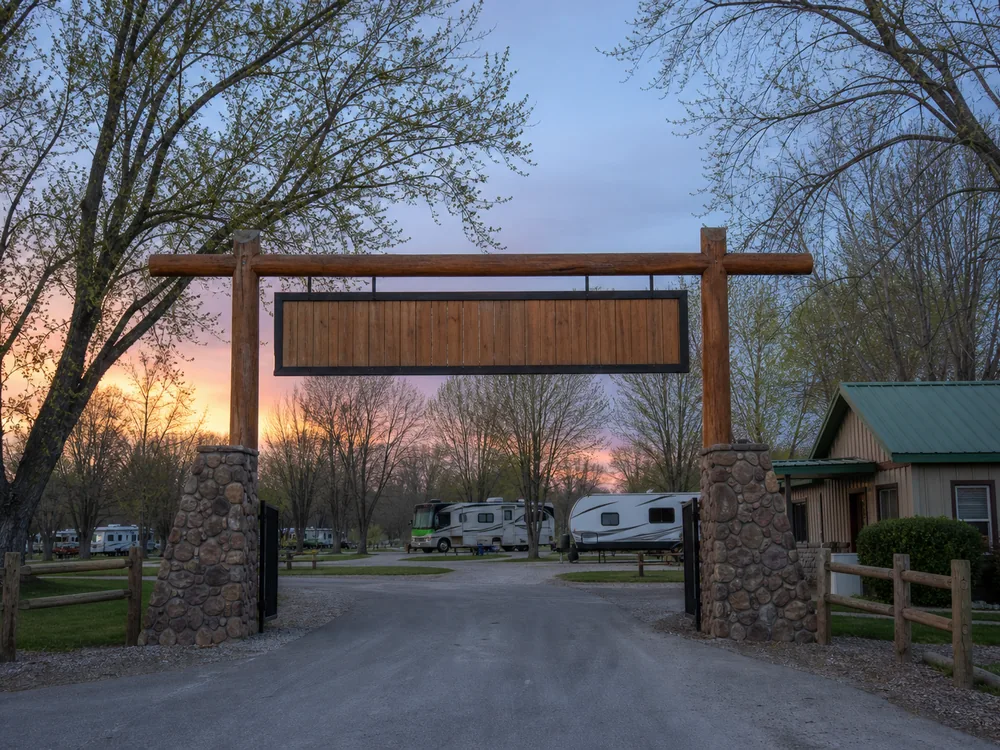 Entry gate and welcome sign at an RV park in dawn cool light