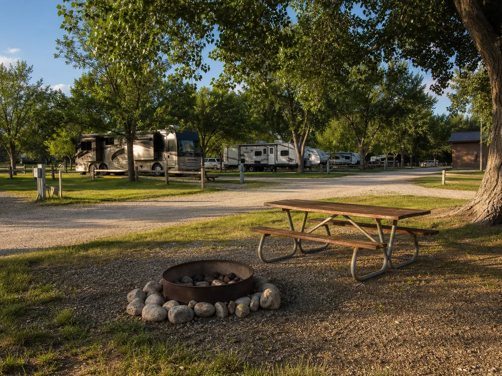 Fire ring and picnic table at an RV park in late afternoon side light