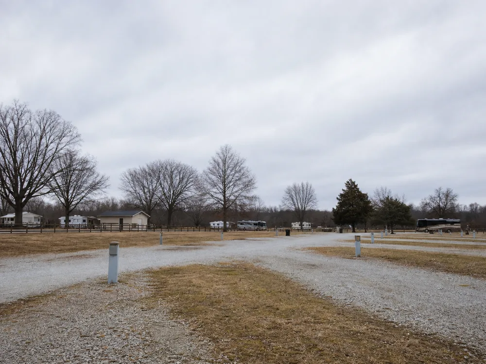Empty gravel RV sites with hookup pedestals under flat winter sky